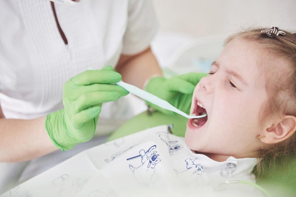 Teeth checkup at dentist's office. Dentist examining girls teeth in the dentists chair